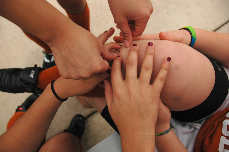 Simone Lumsden’s teammates help her pop a blood bubble from a previous game.