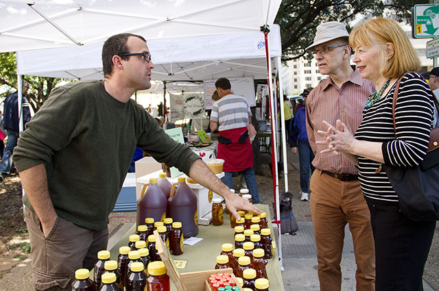 Mark Bradley talks with Marc Trudeau and Cornelia Brandt at the Downtown Farmers' Market about the differences in the types of honey he sells. Photo by Oscar Ricardo Silva