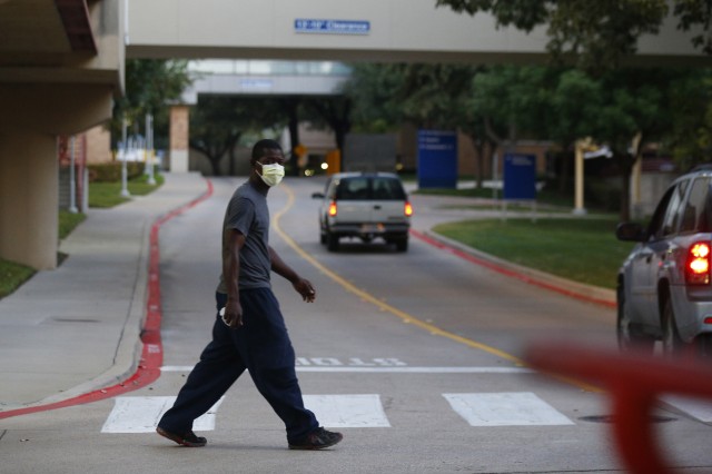A pedestrian wears a surgical mask as he crosses the street in front of Texas Health Presbyterian Hospital Thursday morning, Oct. 2, 2014, in Dallas, where Thomas Eric Duncan, the Ebola patient who traveled from Liberia to Dallas last week, is being treated.  AP Photo/The Dallas Morning News, Nathan Hunsinger