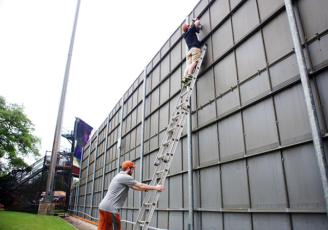 Keith Allen holds a ladder stable for Reed Hauser, both video assistants for The University of Texas baseball team, as he puts a video camera up in the centerfield wall at the UFCU Disch-Falk Field. The three-member teams records every game so that the baseball team can then use the footage to critique their plays. Photo by Kiera Dieter