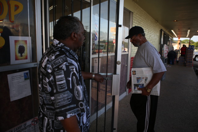 Grayson Crayton walks into William Barbershop on E MLK in East Austin to deliver the week's issue of The Villager. Destinee Harris/Reporting Texas