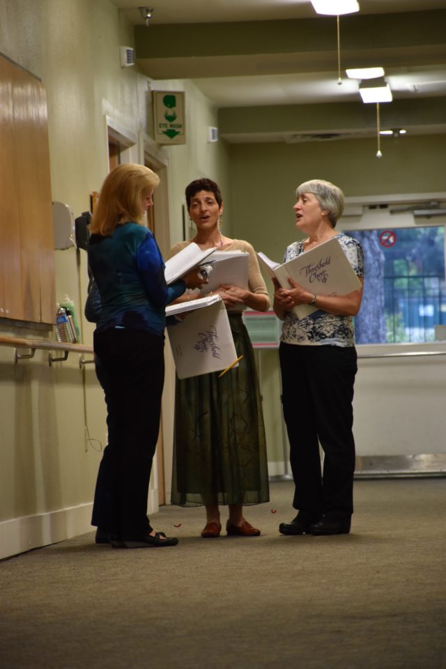 Lora Weber (left), Julie Slim (center) and Elizabeth Stehl (right) sing in the hallway of Hospice Austin’s Christopher House for the three patients present in the surrounding rooms. Destinee Reyes/Reporting Texas