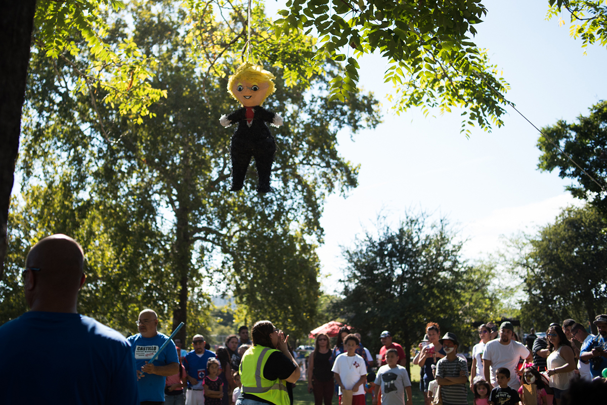 A crowd gathers to smash a Trump piñata at Chicano Park in East Austin on October 9. Adults destroyed two of the piñatas during a Sunday afternoon lowrider car meet-up. Graham Dickie/Reporting Texas